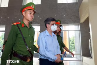 Lực lượng chức năng dẫn giải bị cáo Nguyễn Thanh Long (cựu Bộ trưởng Bộ Y tế) đến phiên tòa. (Ảnh: Phạm Kiên/TTXVN)