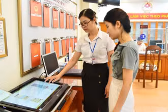 Cán bộ Ủy ban nhân dân phường Thanh Xuân Nam (quận Thanh Xuân, Hà Nội) hướng dẫn người dân thực hiện thủ tục hành chính trên môi trường mạng. (Ảnh: Thủy Nguyên/Báo Nhân Dân)