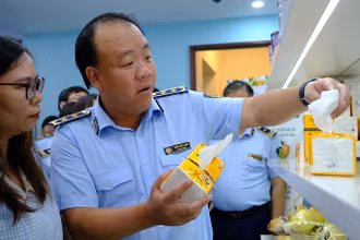 Tổng cục trưởng Quản lý thị trường Trần Hữu Linh giúp khách tham quan phân biệt sản phẩm giấy ăn thật - giả.