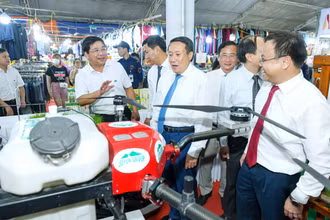 Lãnh đạo Tổng công ty Thương mại Quảng Trị giới thiệu mặt hàng máy bay không người lái phun phân bón và thuốc bảo vệ thực vật hữu cơ cho lúa với du khách và đại biểu.