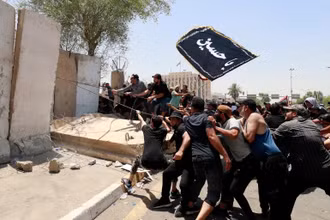 Người biểu tình kéo đổ 1 mảng tường bao quanh Vùng Xanh ở Baghdad. (Ảnh: Getty Images) 