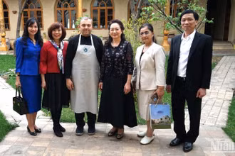 Phu nhân Chủ tịch Quốc hội và các thành viên tháp tùng chụp ảnh kỷ niệm với chủ gia đình cơ sở trưng bày gốm truyền thống Uzbekistan.