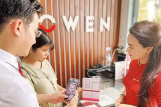 Nhân viên ngân hàng hướng dẫn khách hàng thanh toán không dùng tiền mặt. (Ảnh: CTV)