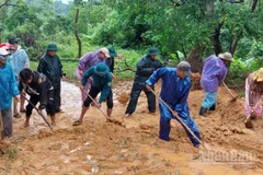 Bộ đội Biên phòng tỉnh cùng người dân dọn dẹp bùn đất trên các tuyến đường sau mưa lũ. 