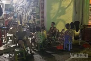 Người dân trên phố Hai Bà Trưng (phường Thái Bình, tỉnh Hưng Yên) dùng đèn ắc quy ngồi chờ trong lúc bị ngừng cấp điện.