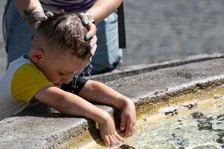 Bà mẹ làm mát cho con nhỏ khi nắng nóng bao trùm thủ đô Rome, Italia ngày 14/7/2024. (Ảnh: THX/TTXVN)