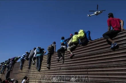 Người di cư trèo qua bức tường biên giới Mexico-Mỹ, gần cửa khẩu El Chaparral ở Tijuana, bang Baja California, Mexico. (Ảnh tư liệu: TTXVN)