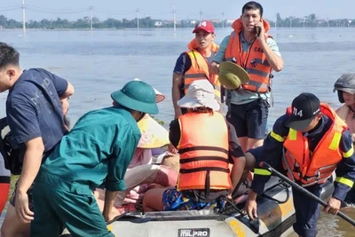 Lực lượng chức năng hỗ trợ người dân ra khỏi khu vực ngập sâu. (Nguồn: Công an thành phố Hà Nội)