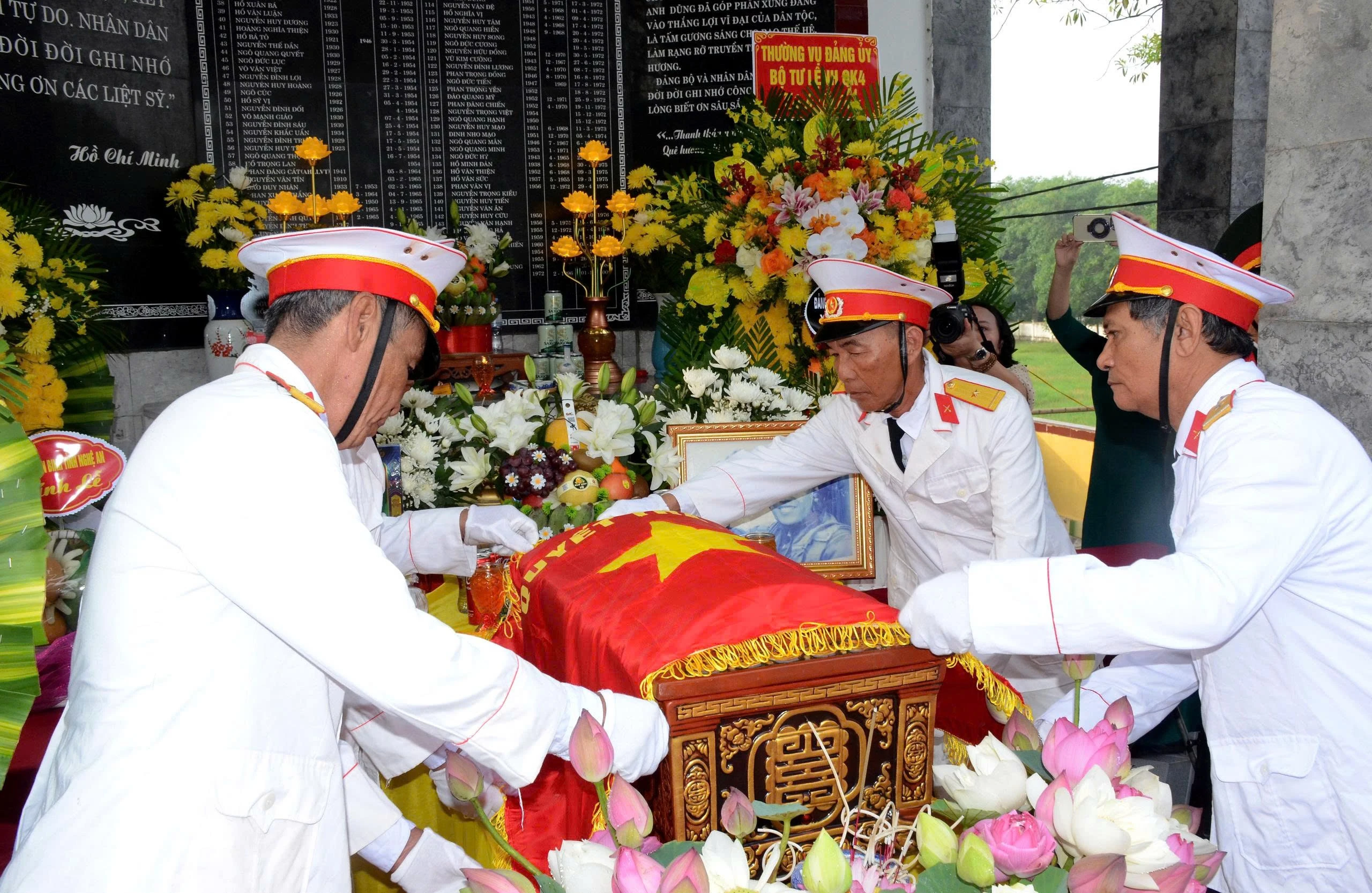 Các cựu chiến binh xã Thông Tân thực hiện nghi thức phủ Quân kỳ cho liệt sĩ Ngô Đức Mai. (Ảnh: THÀNH CHUNG)