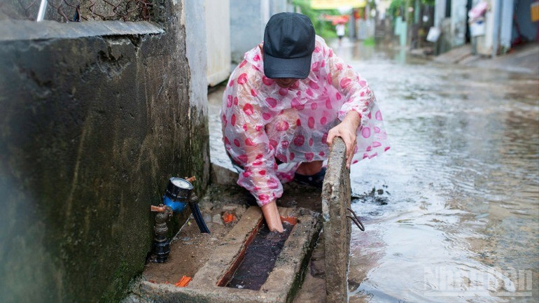 Nhiều người dân tranh thủ dọn dẹp nhà, khơi thông cống thoát nước khi nước rút bớt trong sáng nay. ndo_br_373a5ab7-ec6f-4b08-8a05-b4e39a6f438b-7529.jpg