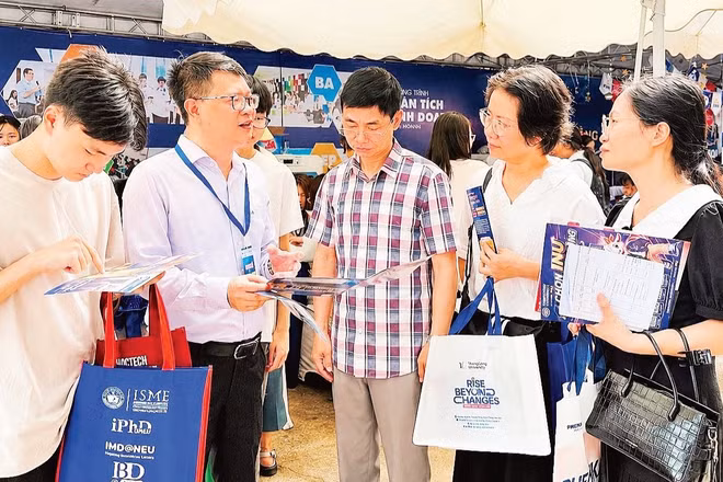 Thí sinh và phụ huynh được giải đáp thông tin tuyển sinh, chương trình đào tạo tại gian tư vấn của Đại học Kinh tế quốc dân. (Ảnh: QUỲNH NGUYỄN)