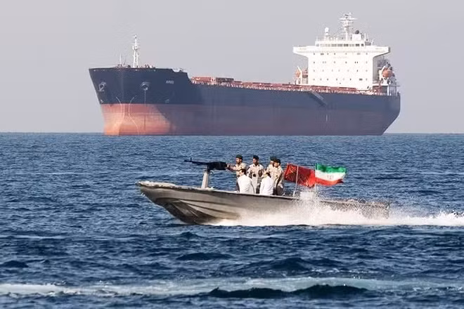 Lực lượng an ninh Iran tuần tra cạnh một tàu hàng ở Eo biển Hormuz. (Ảnh: GETTYIMAGES)