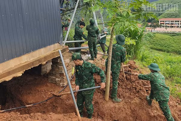 Cán bộ, chiến sĩ Đồn Biên phòng Cửa khẩu quốc tế Lóng Sập giúp hộ gia đình tại bản Bó Sập khắc phục hậu quả sạt lở đất. (Ảnh: QUÀNG HÙNG)