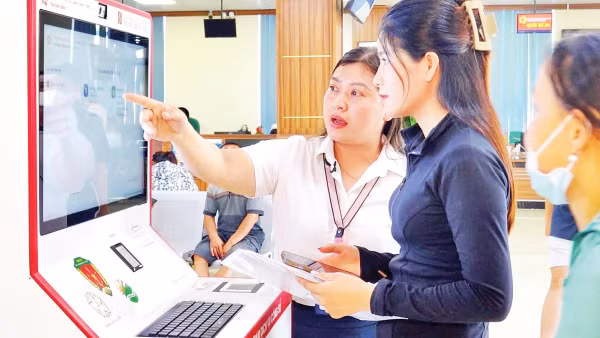Cán bộ hướng dẫn người dân thực hiện thủ tục hành chính tại Trạm dịch vụ công số, Trung tâm Phục vụ hành chính công tỉnh Ninh Bình. 