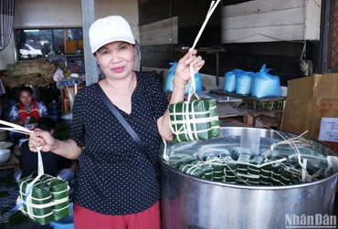 Cô Mai, người có thể gói 200 chiếc bánh chưng trong một buổi sáng, hào hứng khoe mẻ bánh đang được xếp vào nồi. (Ảnh: TRỊNH DŨNG)