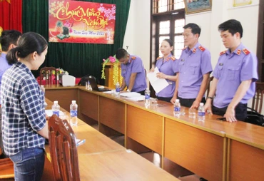 Phan Thị Anh (bên trái) đang nghe cơ quan chức năng tống đạt quyết định khởi tố.