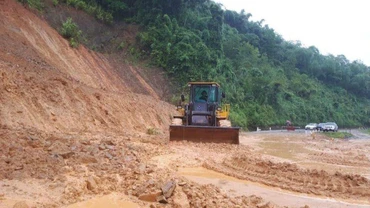 Tập trung san gạt đất lở tại dốc Chó, xã Lạng Khê (Con Cuông) để thông xe trên quốc lộ 7 kịp thời.