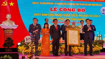 Thừa ủy nhiệm Thủ tướng Chính phủ, Thứ trưởng Xây dựng Nguyễn Tường Văn (phải) trao Quyết định công nhận thành phố Dĩ An là đô thị loại II cho lãnh đạo thành phố Dĩ An. 