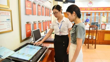 Cán bộ Ủy ban nhân dân phường Thanh Xuân Nam (quận Thanh Xuân, Hà Nội) hướng dẫn người dân thực hiện thủ tục hành chính trên môi trường mạng. (Ảnh: Thủy Nguyên/Báo Nhân Dân)
