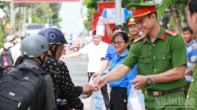 Cán bộ, chiến sĩ công an phát nước suối và khăn lạnh cho người dân về quê nghỉ lễ.