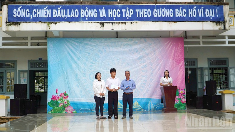Em Trần Lê Nguyễn nhận tiền hỗ trợ của Quỹ xã hội Cỏ May tại sân trường.