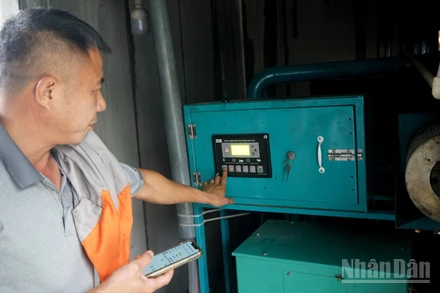 Ông Trần Xuân Phong vận hành máy phát điện từ khí biogas. (Ảnh: TRUNG HƯNG)