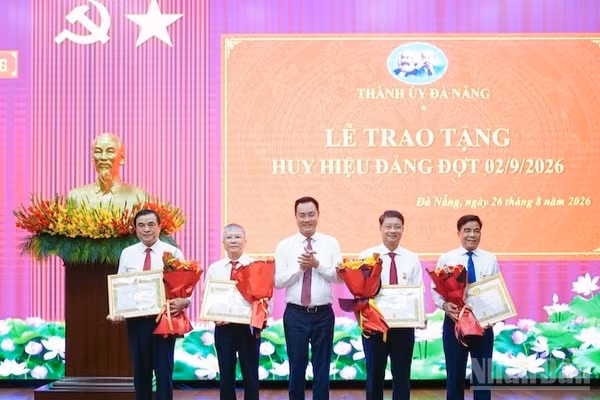 Bí thư Thành ủy Đà Nẵng Lê Ngọc Quang trao Huy hiệu Đảng và tặng hoa chúc mừng các đảng viên. (Ảnh: ANH ĐÀO)