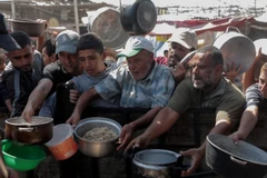 Người dân nhận thức ăn cứu trợ tại thành phố Khan Younis, Dải Gaza. (Ảnh: THX/TTXVN)