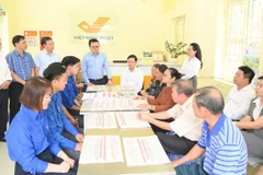 Tổng Biên tập Lê Quốc Minh trao đổi với người dân về dự thảo các văn kiện trình Đại hội XIV do Báo Nhân Dân trưng bày tại Bưu điện Văn hóa xã Tân Hưng, tỉnh Hưng Yên. (Ảnh THẾ ĐẠI)