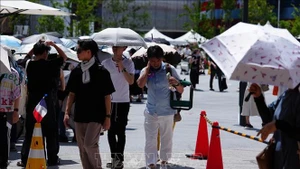 Người dân di chuyển trên đường phố dưới trời nắng nóng tại Osaka, Nhật Bản. (Ảnh: TTXVN)