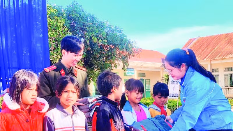 Chị Huỳnh Thị Mai Yến trao áo ấm tặng các em học sinh đồng bào dân tộc thiểu số.