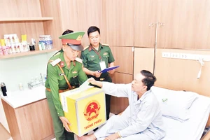 Bệnh nhân Bệnh viện Quân y 175 bỏ phiếu vào thùng phiếu di động. (Ảnh TÙNG LÂM)