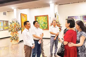 Họa sĩ Trần Giang Nam (ngoài cùng bên trái) trao đổi với người yêu tranh khắc gỗ tại triển lãm cá nhân ở Hà Nội.