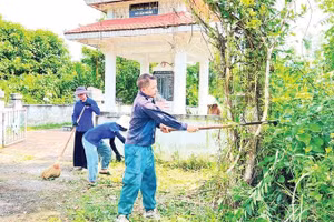 Anh Triệu Văn Nam, Bí thư Chi bộ, Trưởng thôn Nà Tu, xã Cẩm Giàng cùng đoàn viên, thanh niên vệ sinh Đài tưởng niệm liệt sĩ xã (Ảnh TUẤN SƠN)