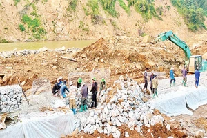 Công nhân Công ty cổ phần đường bộ 2 tập trung khắc phục Quốc lộ 12, đoạn Km 261+900 (Pá Vạt-Mường Luân) bị lũ cuốn mất toàn bộ mặt đường.