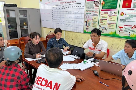 Cán bộ công vụ xã Khánh Hưng, tỉnh Cà Mau tra đối chiếu dữ liệu để phát quà cho người dân địa phương. 