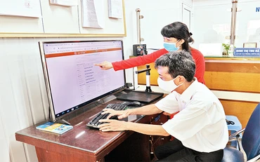 Cán bộ công chức phường Cầu Dền, quận Hai Bà Trưng hướng dẫn người dân nộp hồ sơ trên Cổng dịch vụ công điện tử thành phố Hà Nội. (Ảnh MẠNH KHÁNH)