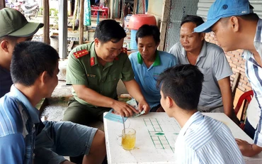 Cán bộ Phòng An ninh kinh tế (Công an tỉnh Hậu Giang) hướng dẫn người dân trên địa bàn thị xã Long Mỹ cách nhận biết tiền giả. Ảnh: THANH DANH