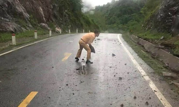 Thiếu tá Đặng Văn Thu bê đá lăn ra khỏi lòng đường để bảo đảm an toàn cho người tham gia giao thông. (Ảnh: Đội Cảnh sát giao thông Na Rì cung cấp)