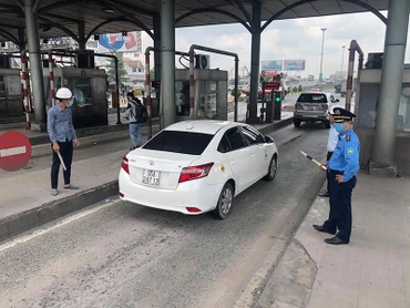 Lực lượng chức năng hướng dẫn xe qua trạm sau khi tạm dừng thu phí.
