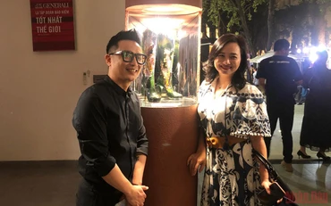 Anh Vũ Khánh Tùng (trái) bên tác phẩm của cha mình để lại.
