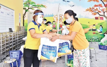 Nhân viên Công ty CP Vàng bạc đá quý Phú Nhuận (PNJ) hỗ trợ người dân tại “Siêu thị mini 0 đồng” trên địa bàn Hà Nội. Ảnh: Thủy Nguyên 