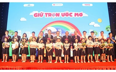 Phó Thủ tướng Trương Hòa Bình và các đại biểu trao tượng trưng mũ bảo hiểm đạt chuẩn cho các học sinh lớp một tại lễ công bố chương trình “Giữ trọn ước mơ” ngày 3-7.