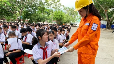 Tuyên truyền viên của Điện lực tỉnh Vĩnh Long phát cẩm nang Tiết kiệm điện cho các em học sinh.