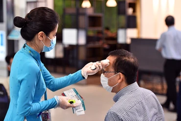 Nhân viên Hãng hàng không Vietnam Airlines đo nhiệt độ cho hành khách, bảo đảm quy định phòng, chống dịch.