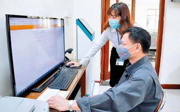 Hỗ trợ người dân thực hiện dịch vụ công trực tuyến tại bộ phận một cửa quận Hai Bà Trưng. (Ảnh NGUYỄN HẠNH)