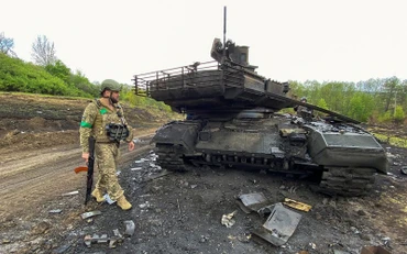 Binh sĩ Ukraine cạnh 1 xe tăng bị phá hủy gần làng Staryi Saltiv ở Kharkov, Ukraine ngày 9/5/2022. (Ảnh: Reuters)