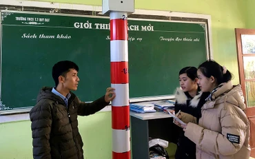 Hai học sinh Trang và Như trao đổi với thầy giáo Cao Ngọc Giang về thiết bị cảnh báo mực nước thông minh.