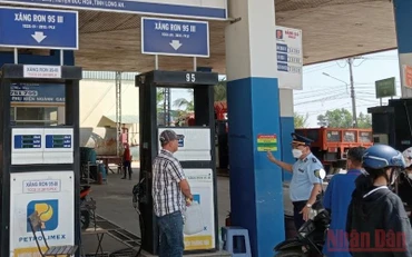Lực lượng quản lý thị trường tỉnh Long An kiểm tra, giám sát và dán thông tin số điện thoại đường dây nóng để tiếp nhận phản ánh của người dân tại cửa hàng xăng, dầu Quốc Minh, xã Mỹ Hạnh Bắc, huyện Đức Hoà, tỉnh Long An.