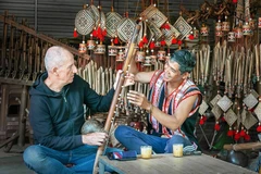 Du khách người Ý thích thú tìm hiểu các nhạc cụ truyền thống Gia Rai dưới sự hướng dẫn của Nghệ nhân Ưu tú Rơ Châm Tih. Ảnh: Nguyễn Linh Vinh Quốc